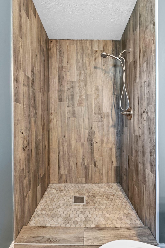 full bath featuring a shower stall and a textured ceiling