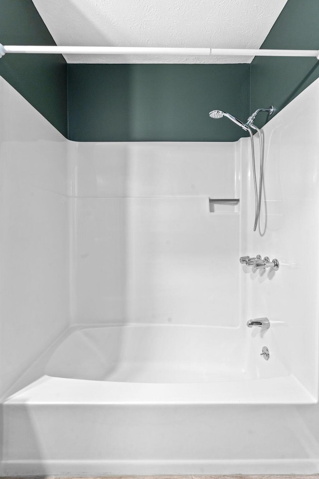 full bathroom with a textured ceiling and washtub / shower combination