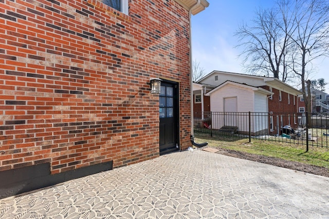 property entrance with brick siding, a patio area, and fence