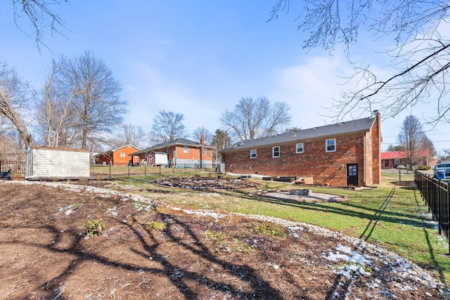 back of property featuring brick siding, a chimney, fence, and a lawn