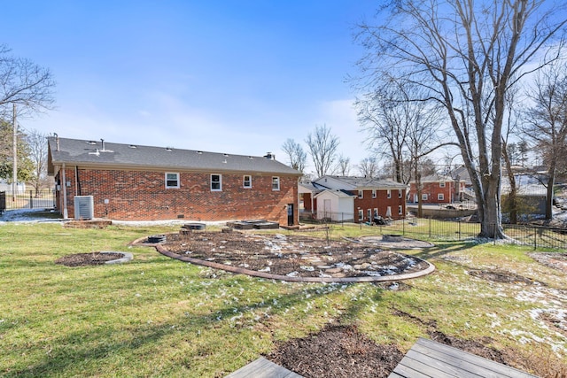 rear view of property with central air condition unit, fence, a lawn, and brick siding