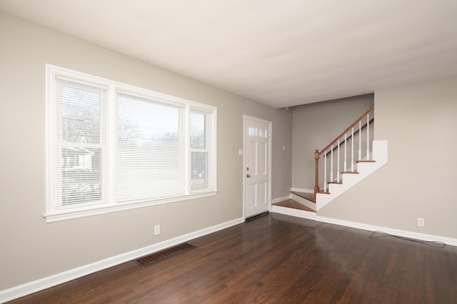 foyer entrance with dark wood-style floors, baseboards, stairs, and visible vents