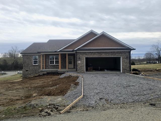 view of front facade with brick siding, covered porch, driveway, and a garage