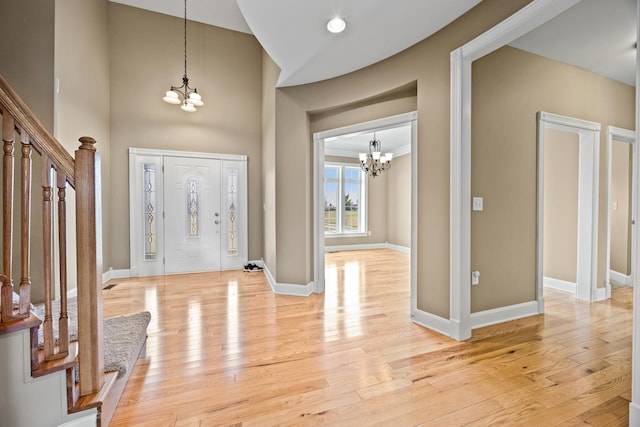 entrance foyer with baseboards, a chandelier, stairs, and light wood finished floors