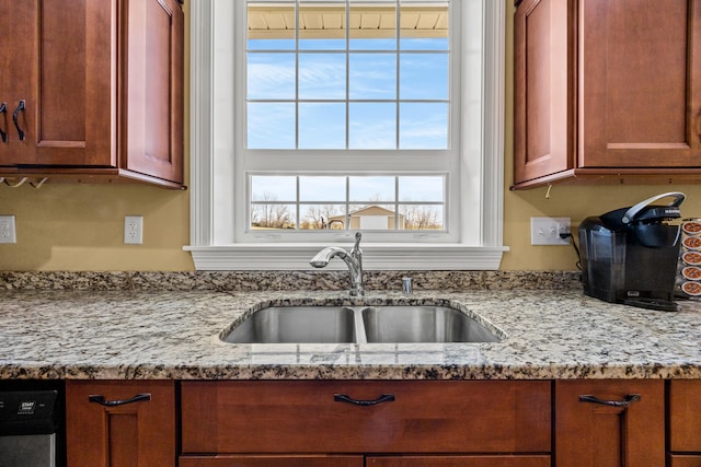 kitchen featuring a sink, light stone counters, and stainless steel dishwasher