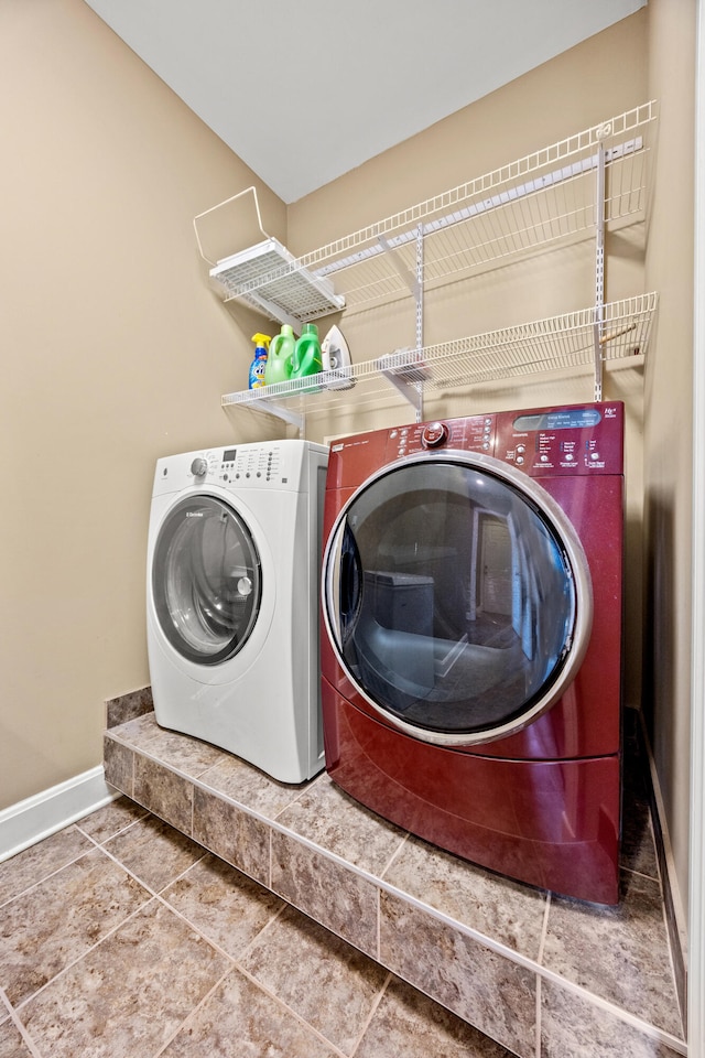 clothes washing area with laundry area, washing machine and dryer, and baseboards