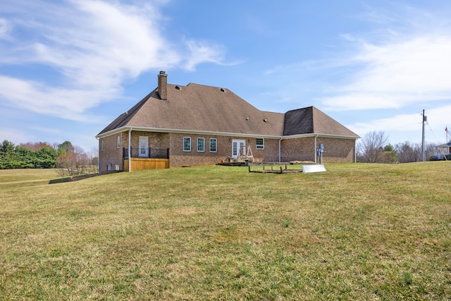 back of property featuring brick siding, a chimney, a yard, and a shingled roof