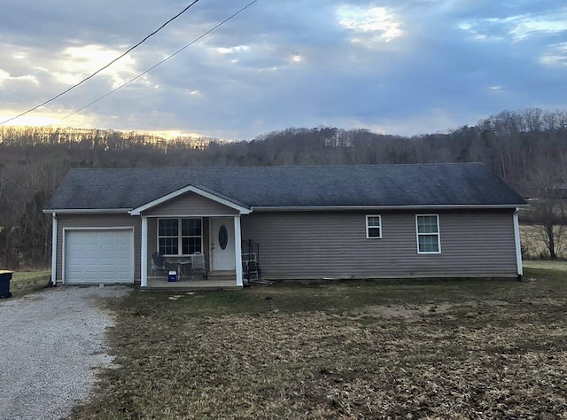 ranch-style house with gravel driveway, covered porch, and an attached garage