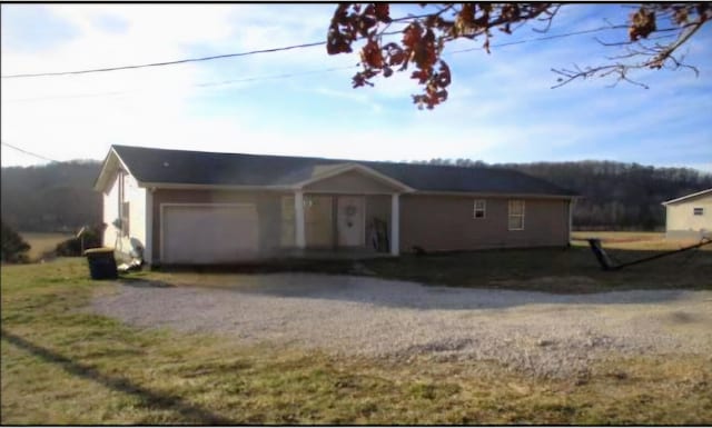 ranch-style home featuring an attached garage and gravel driveway