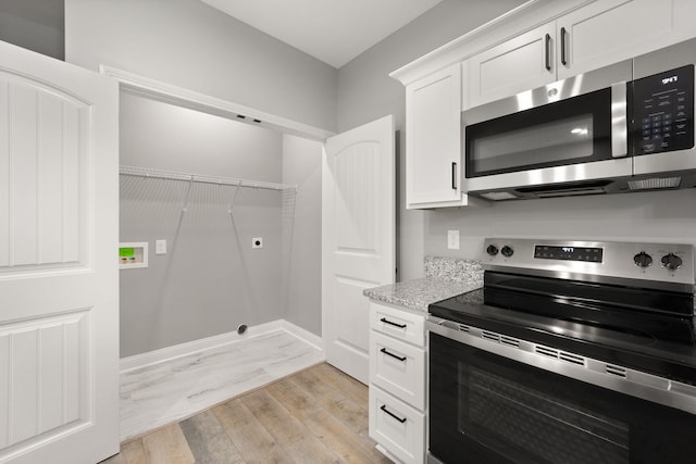 kitchen featuring white cabinetry, stainless steel appliances, light stone counters, and light hardwood / wood-style flooring