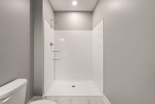 bathroom with a tile shower and toilet