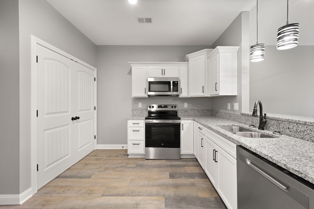 kitchen featuring sink, white cabinetry, hanging light fixtures, stainless steel appliances, and light stone countertops