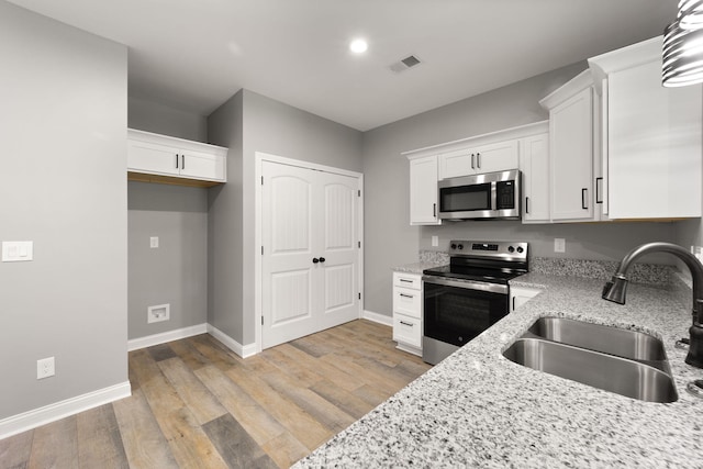 kitchen featuring appliances with stainless steel finishes, sink, white cabinets, and light stone counters