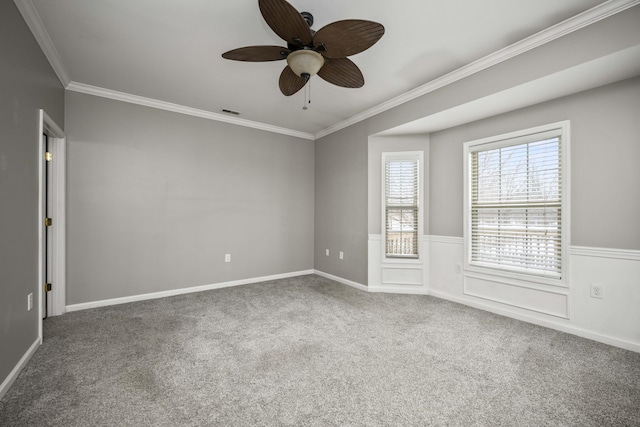 unfurnished room featuring visible vents, wainscoting, ceiling fan, crown molding, and carpet flooring