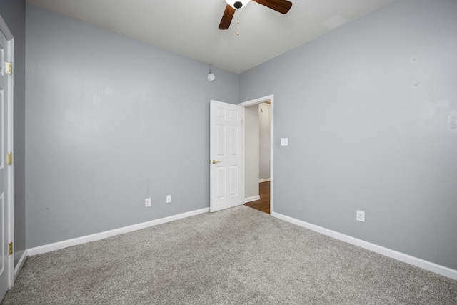 carpeted empty room featuring ceiling fan and baseboards