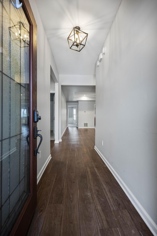 entryway with an inviting chandelier, visible vents, baseboards, and wood finished floors