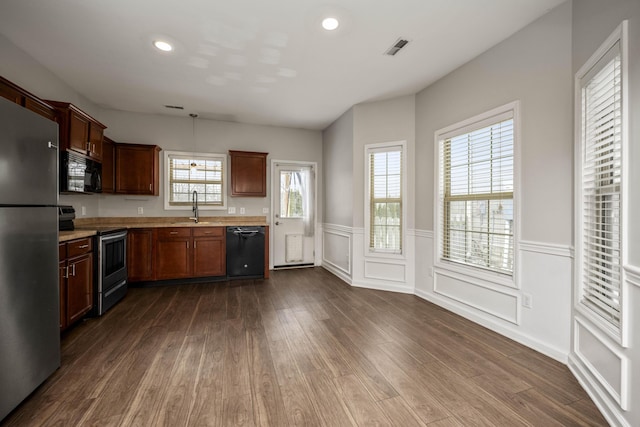 kitchen featuring dark wood-style floors, light countertops, visible vents, a sink, and black appliances