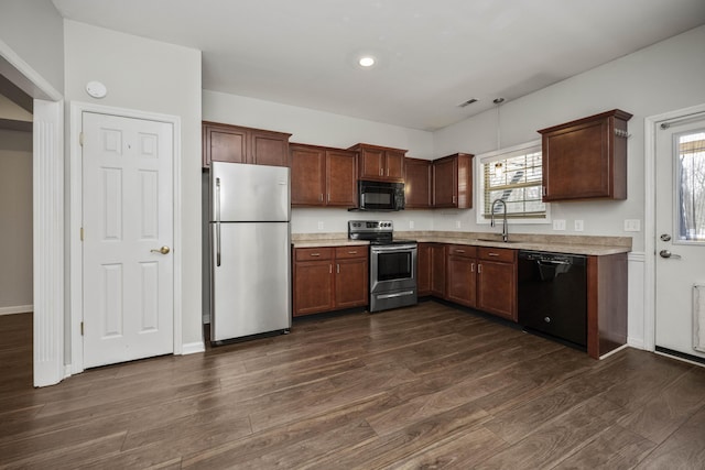 kitchen with light countertops, dark wood finished floors, a sink, and black appliances