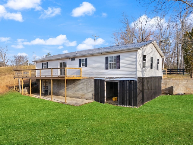 rear view of house featuring a wooden deck, a lawn, and a patio area