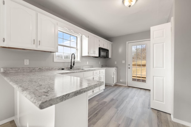 kitchen with kitchen peninsula, sink, and white cabinets