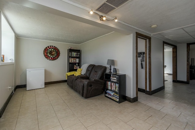 living area featuring crown molding, light tile patterned floors, and a textured ceiling