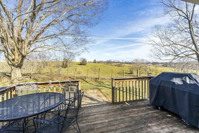 deck with a grill, a lawn, and a rural view