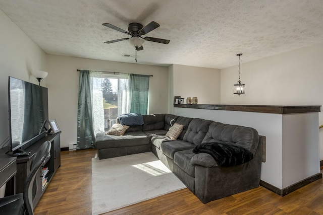 living room featuring dark hardwood / wood-style flooring, ceiling fan, and a textured ceiling