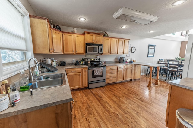 kitchen with stainless steel appliances, recessed lighting, light countertops, light wood-style floors, and a sink