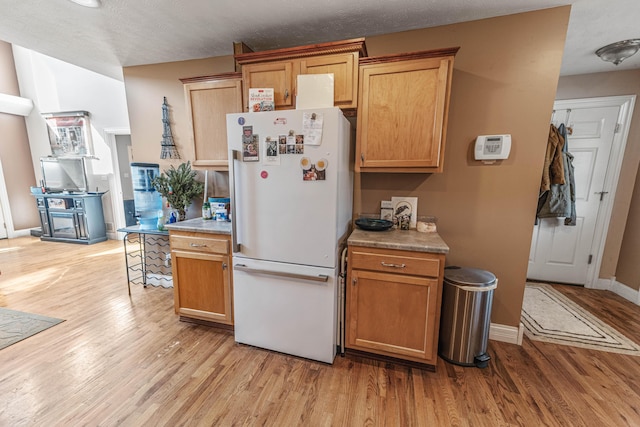 kitchen featuring light wood-style floors, freestanding refrigerator, and light countertops