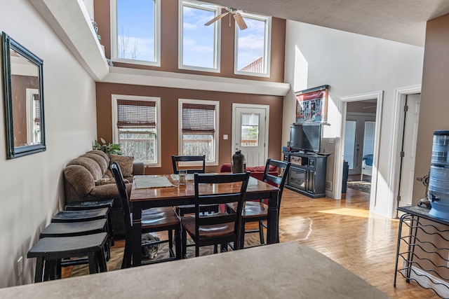 dining space with high vaulted ceiling, light wood finished floors, and a ceiling fan