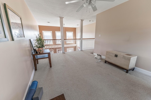 interior space with a textured ceiling, carpet, decorative columns, and baseboards