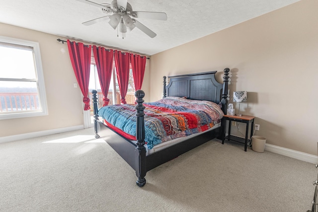 carpeted bedroom with ceiling fan, multiple windows, baseboards, and a textured ceiling