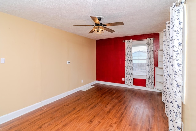 spare room featuring a textured ceiling, a ceiling fan, baseboards, and wood-type flooring