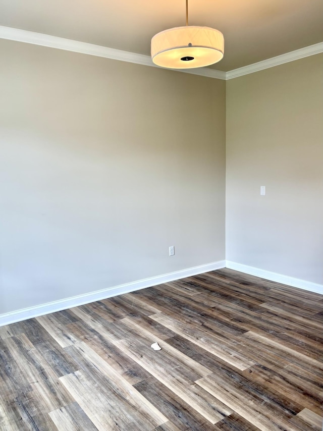 spare room with crown molding, baseboards, and dark wood-style floors