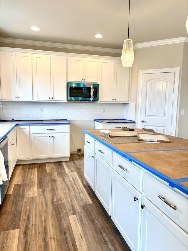 kitchen with white cabinets, backsplash, appliances with stainless steel finishes, and ornamental molding