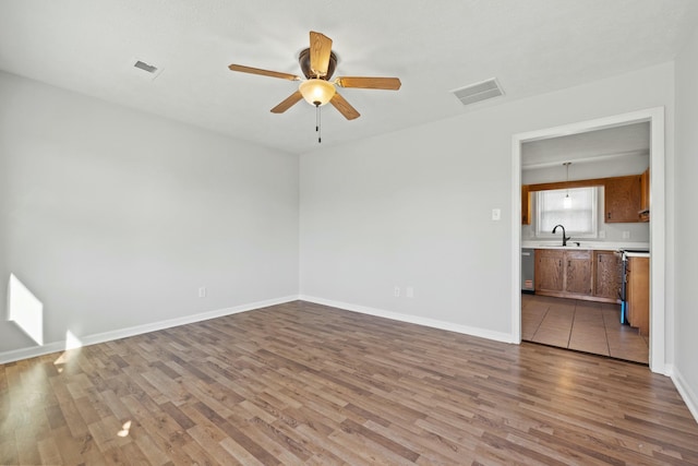 unfurnished living room featuring ceiling fan, sink, and light wood-type flooring