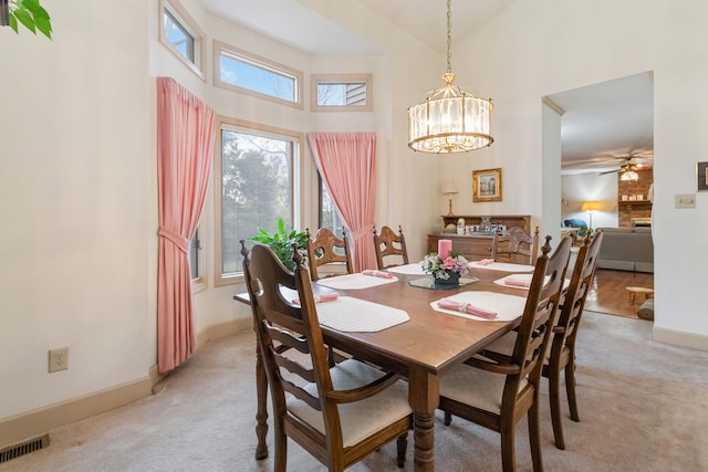 dining room with a towering ceiling and light colored carpet