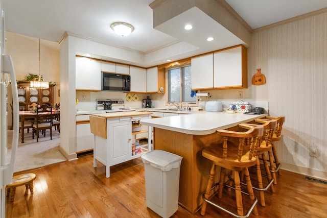 kitchen with white cabinetry, range, a kitchen island, sink, and crown molding