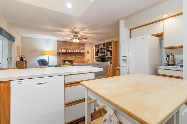 kitchen featuring a fireplace, a center island, ornamental molding, white appliances, and white cabinets