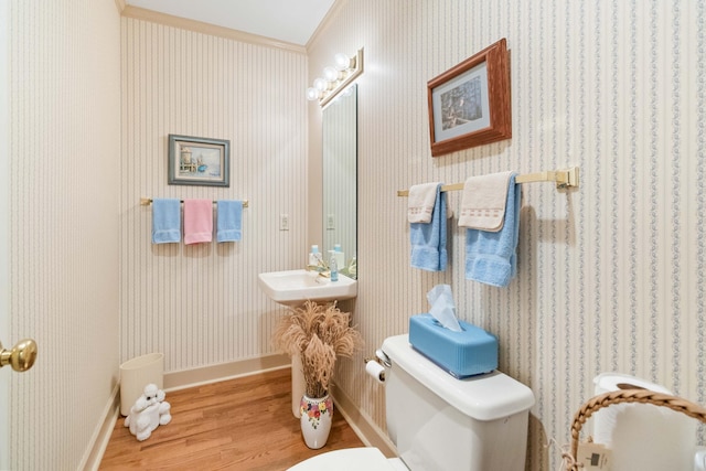 bathroom with toilet, sink, crown molding, and wood-type flooring