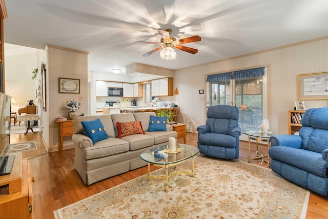 living room featuring ornamental molding, ceiling fan, and light wood-type flooring