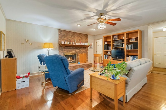 living room featuring hardwood / wood-style floors, ceiling fan, ornamental molding, and a fireplace