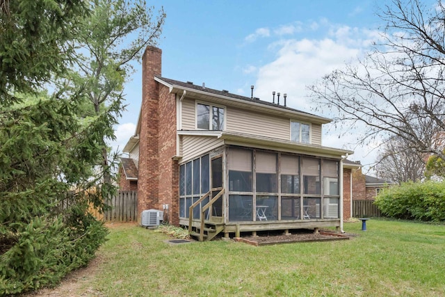 rear view of house featuring a lawn, a sunroom, and central AC unit