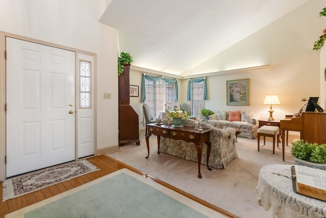 foyer entrance with light hardwood / wood-style floors, a textured ceiling, and lofted ceiling