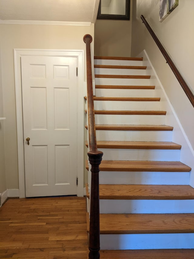 stairs with hardwood / wood-style flooring and ornamental molding