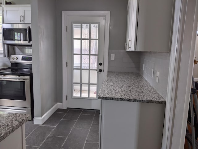 kitchen with white cabinetry, appliances with stainless steel finishes, light stone countertops, and backsplash