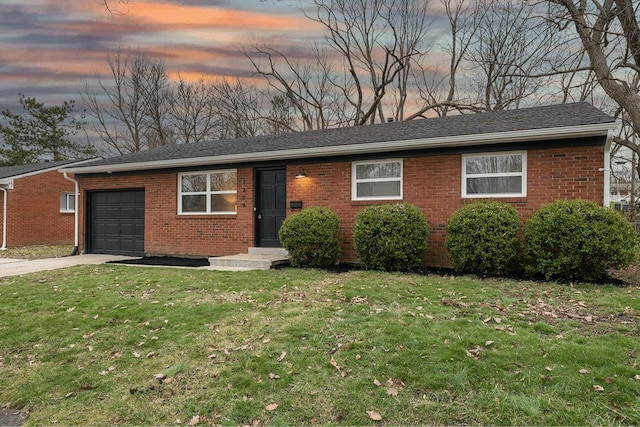 ranch-style house featuring an attached garage, driveway, a front lawn, and brick siding