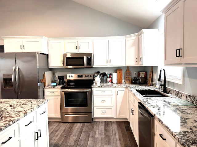 kitchen featuring a sink, stainless steel appliances, light stone countertops, and vaulted ceiling