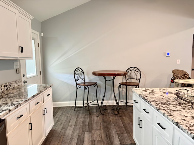 kitchen featuring white cabinetry, light stone countertops, dark wood-style flooring, and baseboards