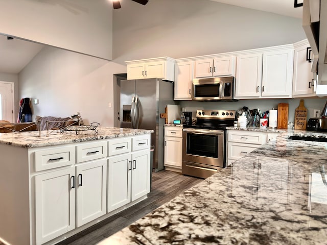 kitchen with light stone counters, dark wood finished floors, white cabinetry, stainless steel appliances, and ceiling fan